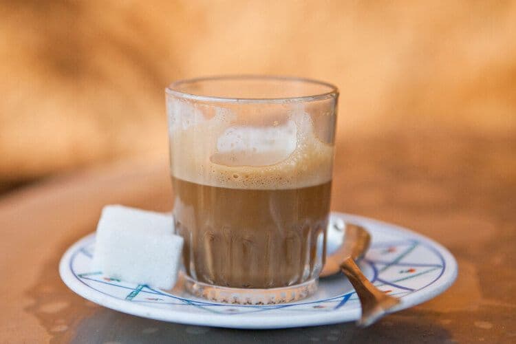 A creamy Spiced coffee in Morocco with sugar cubes.