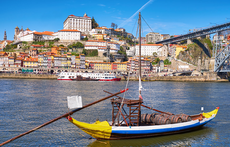 A yellow and wooden boat with wine barrels in the Duoro River in Porto, Portugal